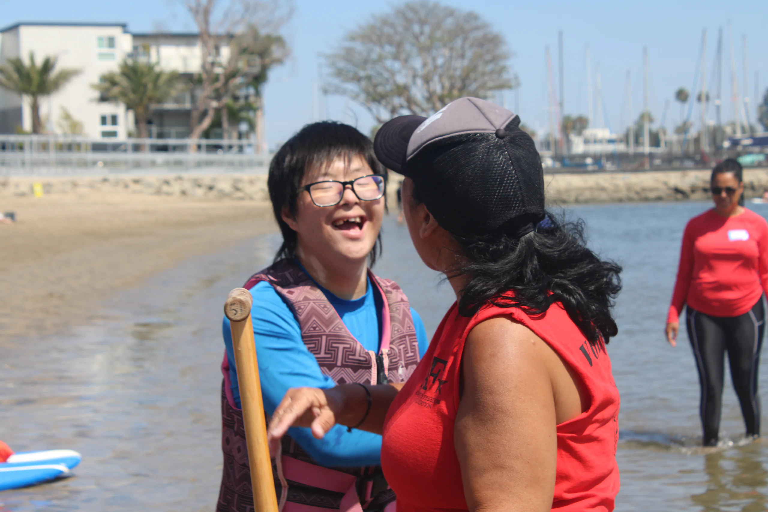 An AFF participant smiling alongside a volunteer at the shoreline