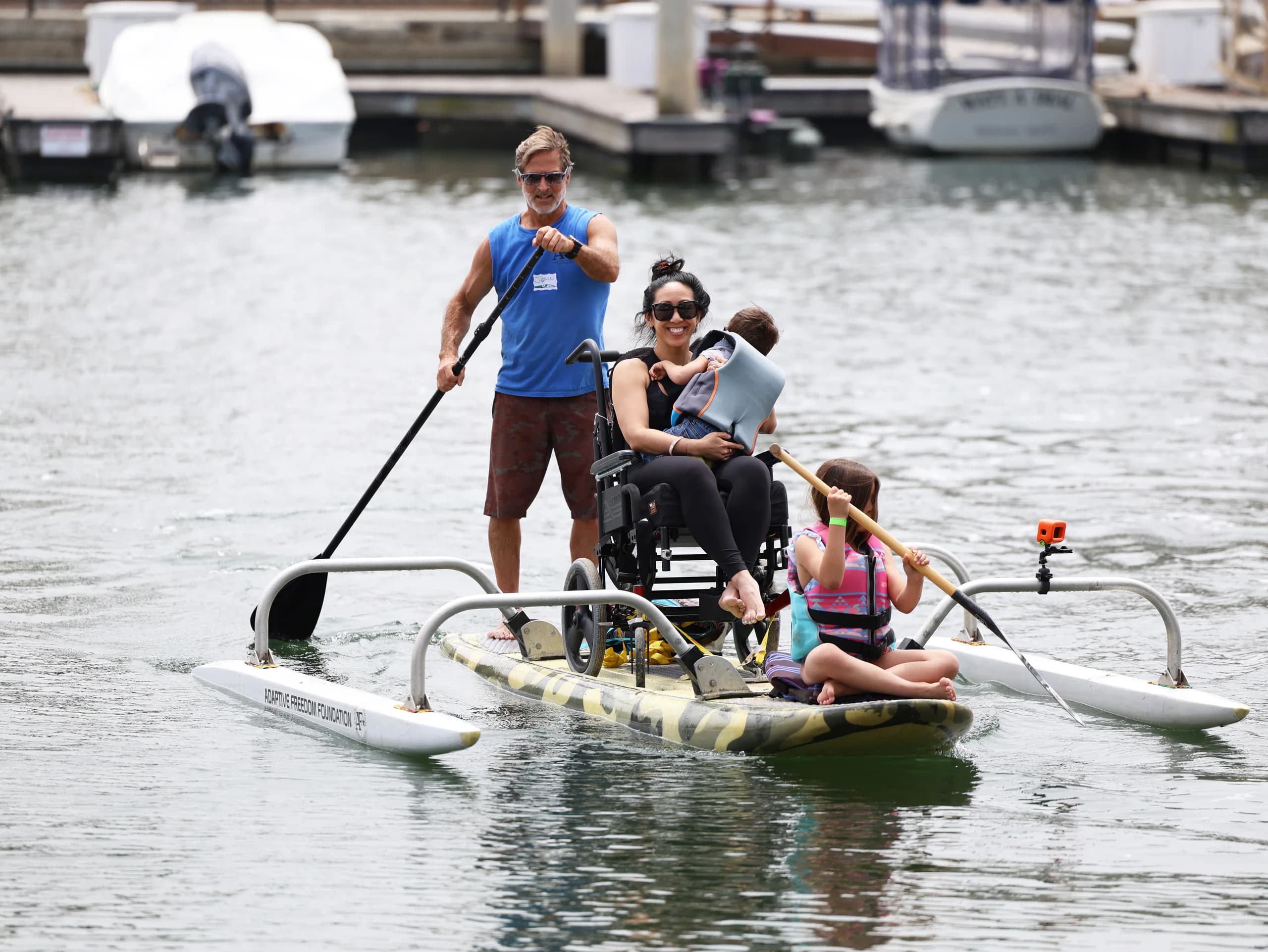 An adaptive paddler supported by an AFF crew member on the water