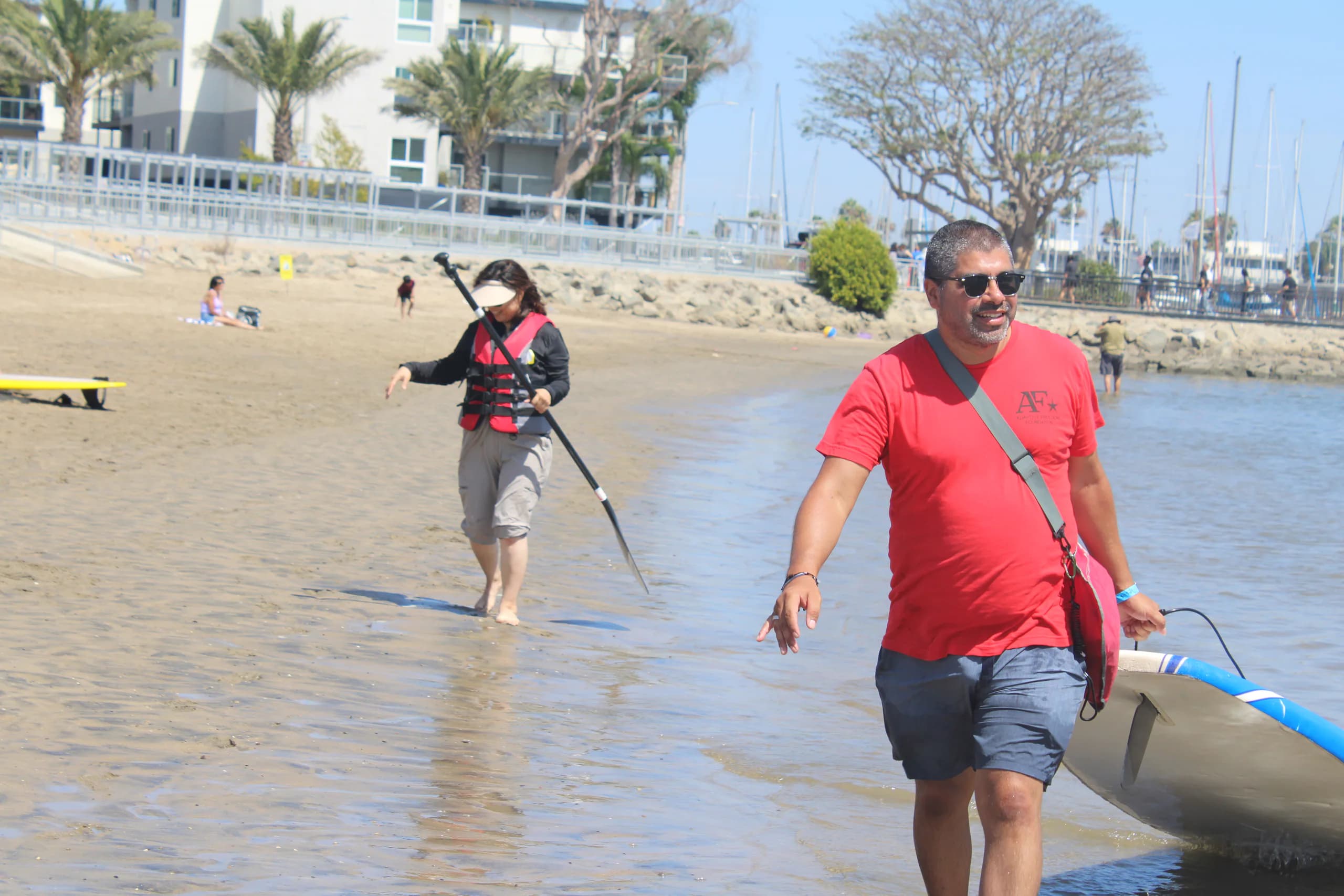 An AFF volunteer carrying a paddle through the shallows