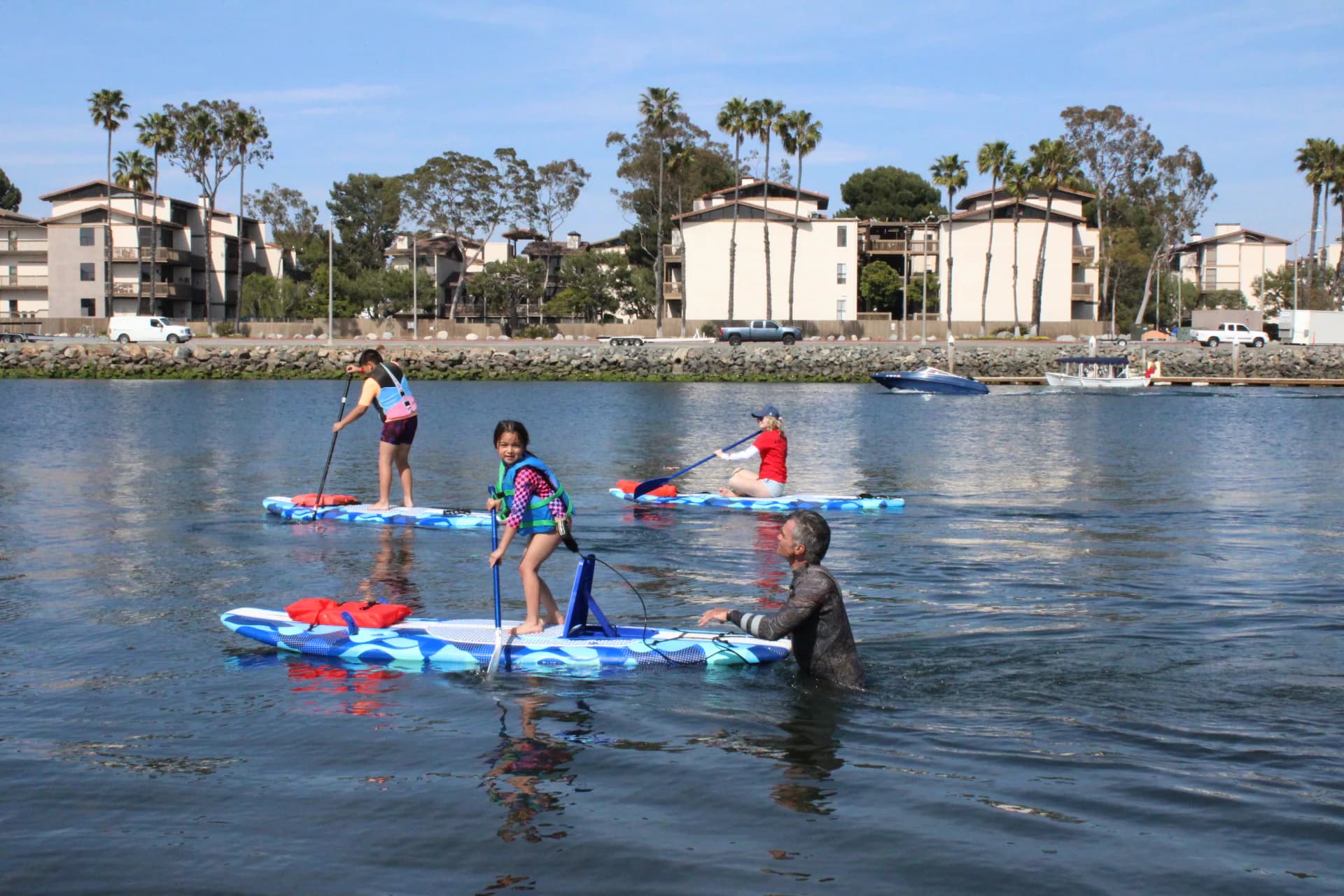 Adaptive paddleboard participants and support crews moving along the shoreline
