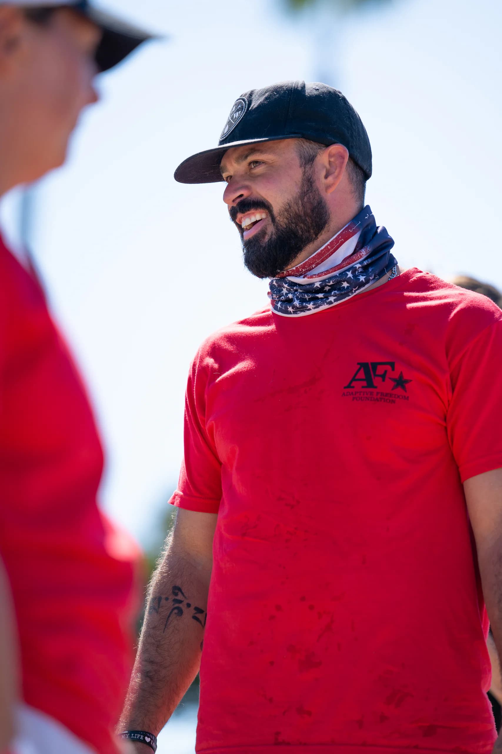 An AFF volunteer smiling in a red shirt and sun hat
