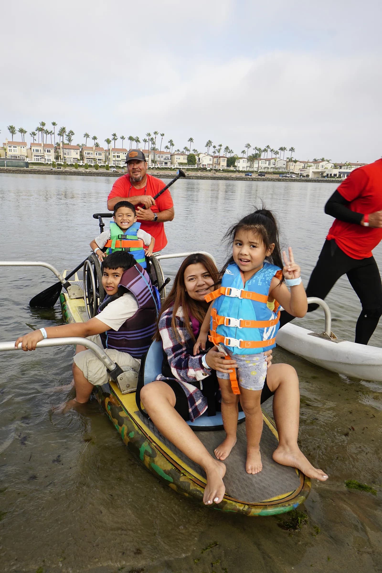 Children, family members, and an AFF volunteer smiling together on an adapted board