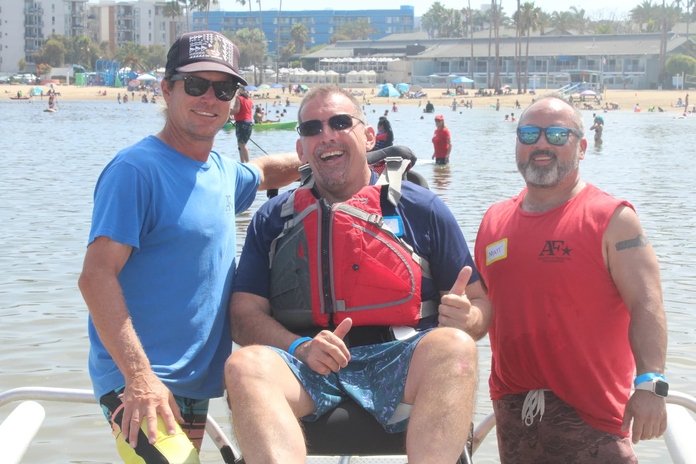 A paddler celebrating on shore with two AFF volunteers