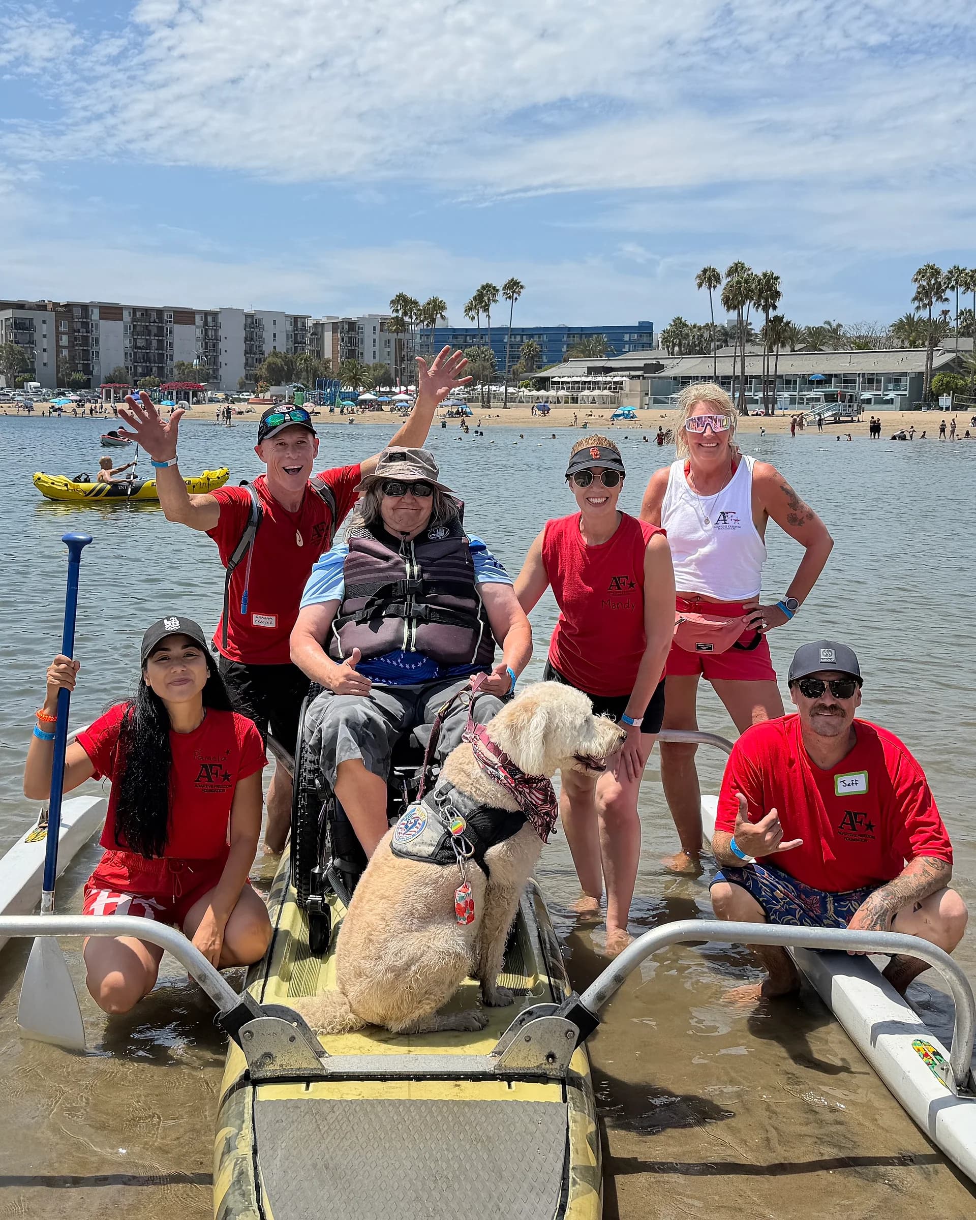 A participant, family members, AFF volunteers, and a service dog gathered on an adapted board