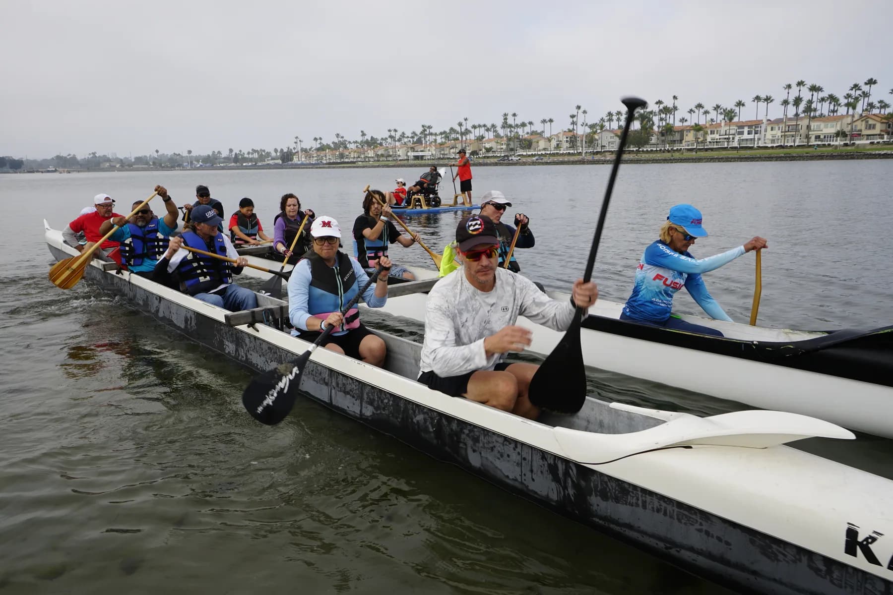 A large adaptive paddling team moving across the water together