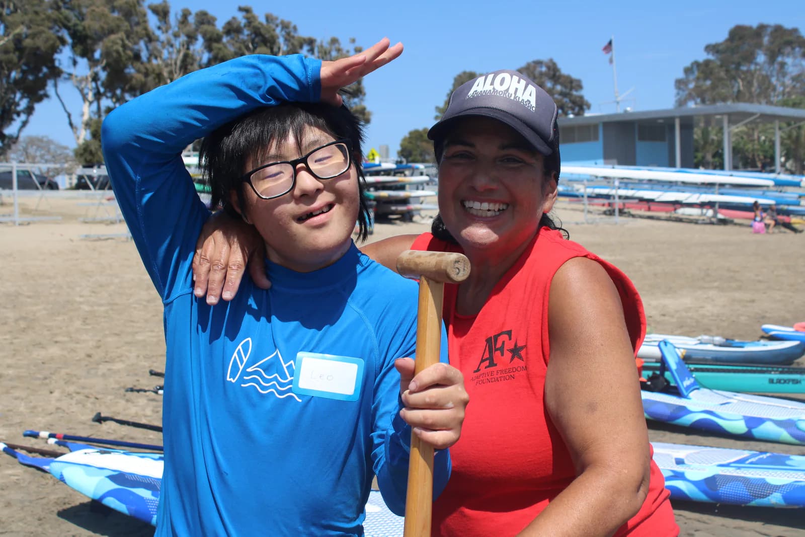 An adaptive paddler and AFF volunteer smiling together on the beach