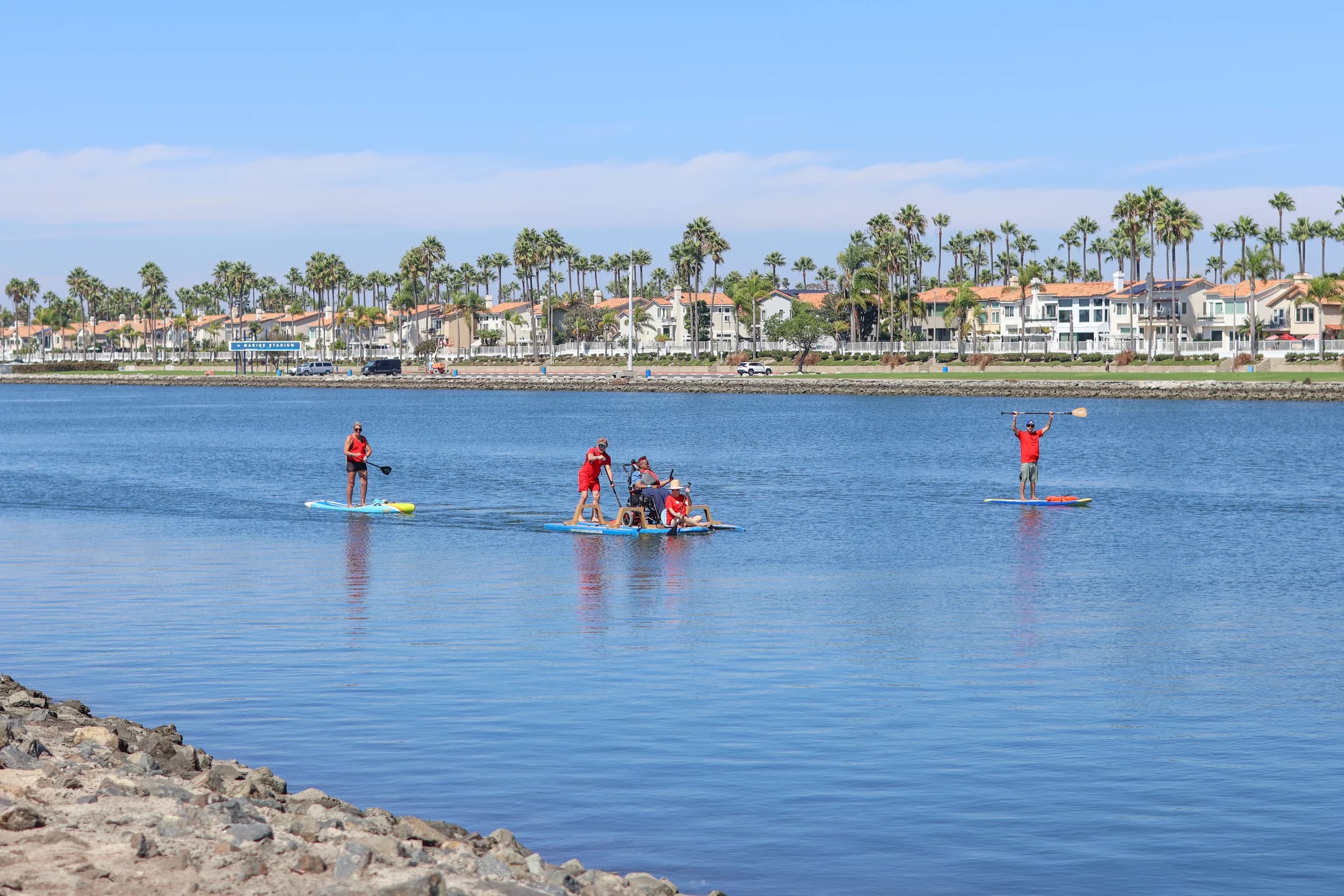 AFF volunteers and an adaptive paddleboard participant cross the calm water at Marine Stadium